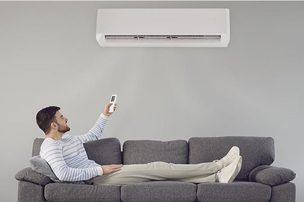 Man lying down on the couch turning on ductless AC